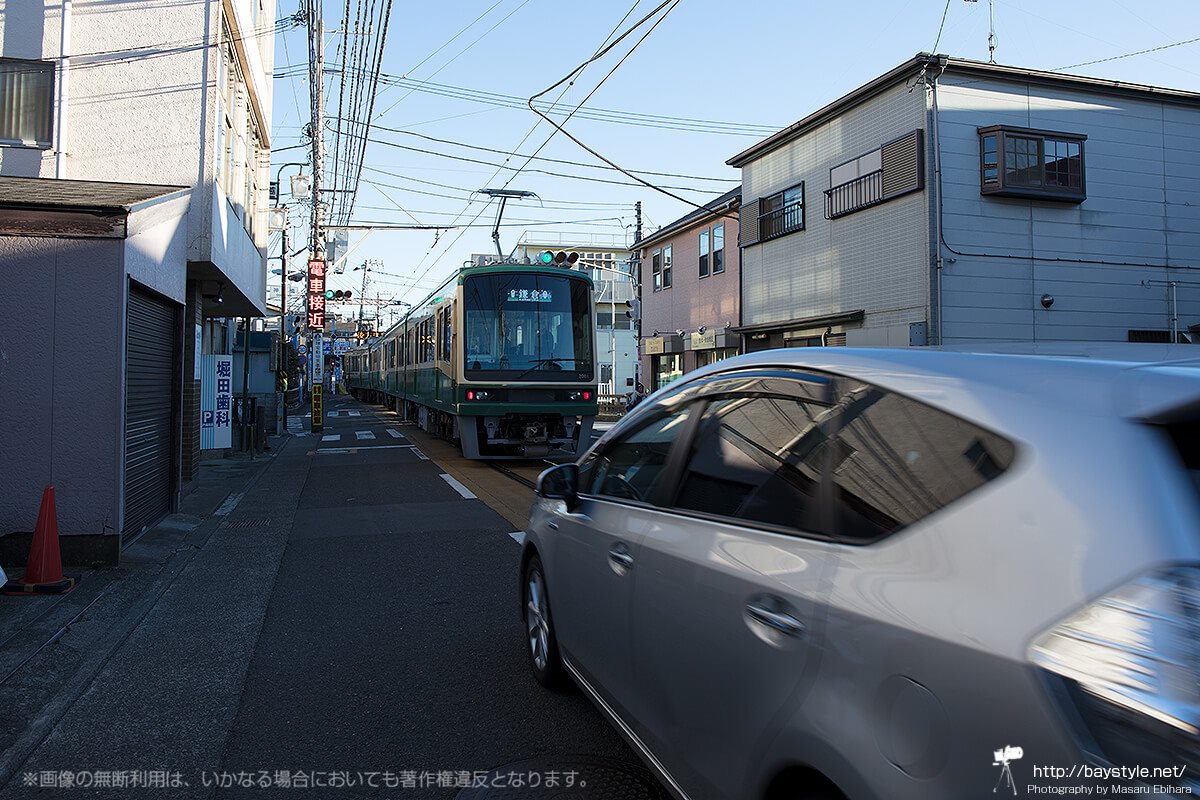 通り過ぎる江ノ電と乗用車